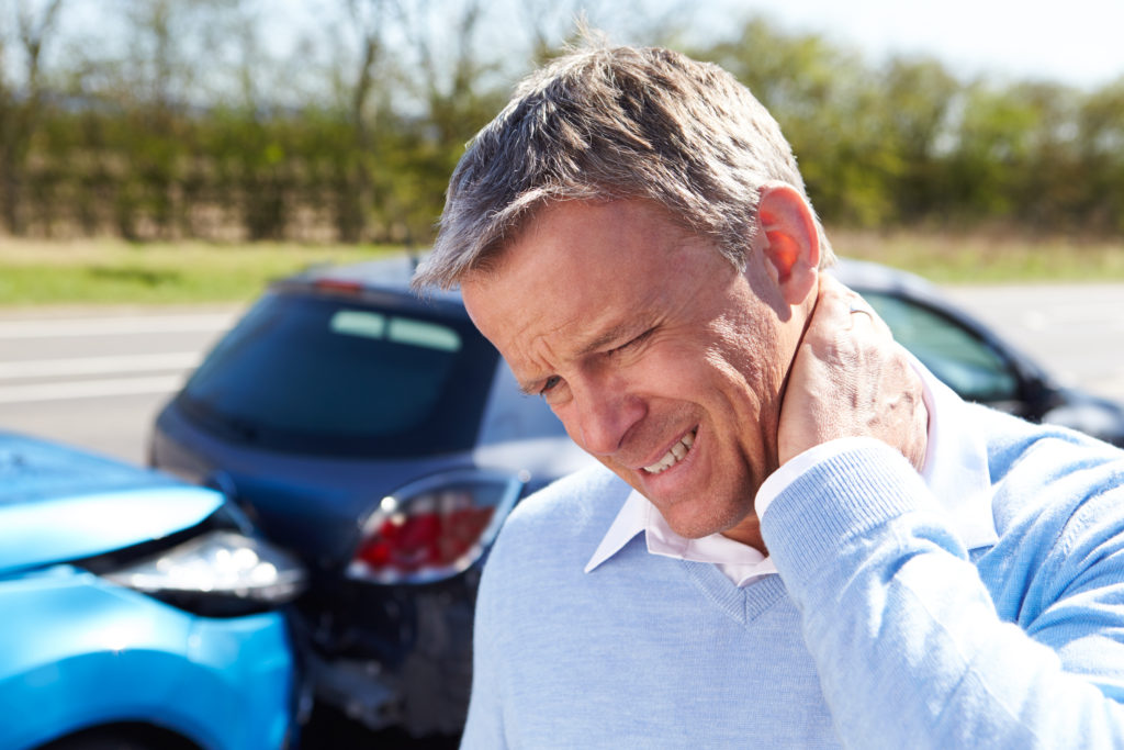 Man holding the back of his neck after an auto accident suffering from whiplash